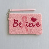 A handmade pink beaded wristlet clutch with a 'Believe' breast cancer awareness ribbon design, featuring red and pink beadwork against a light gray background.