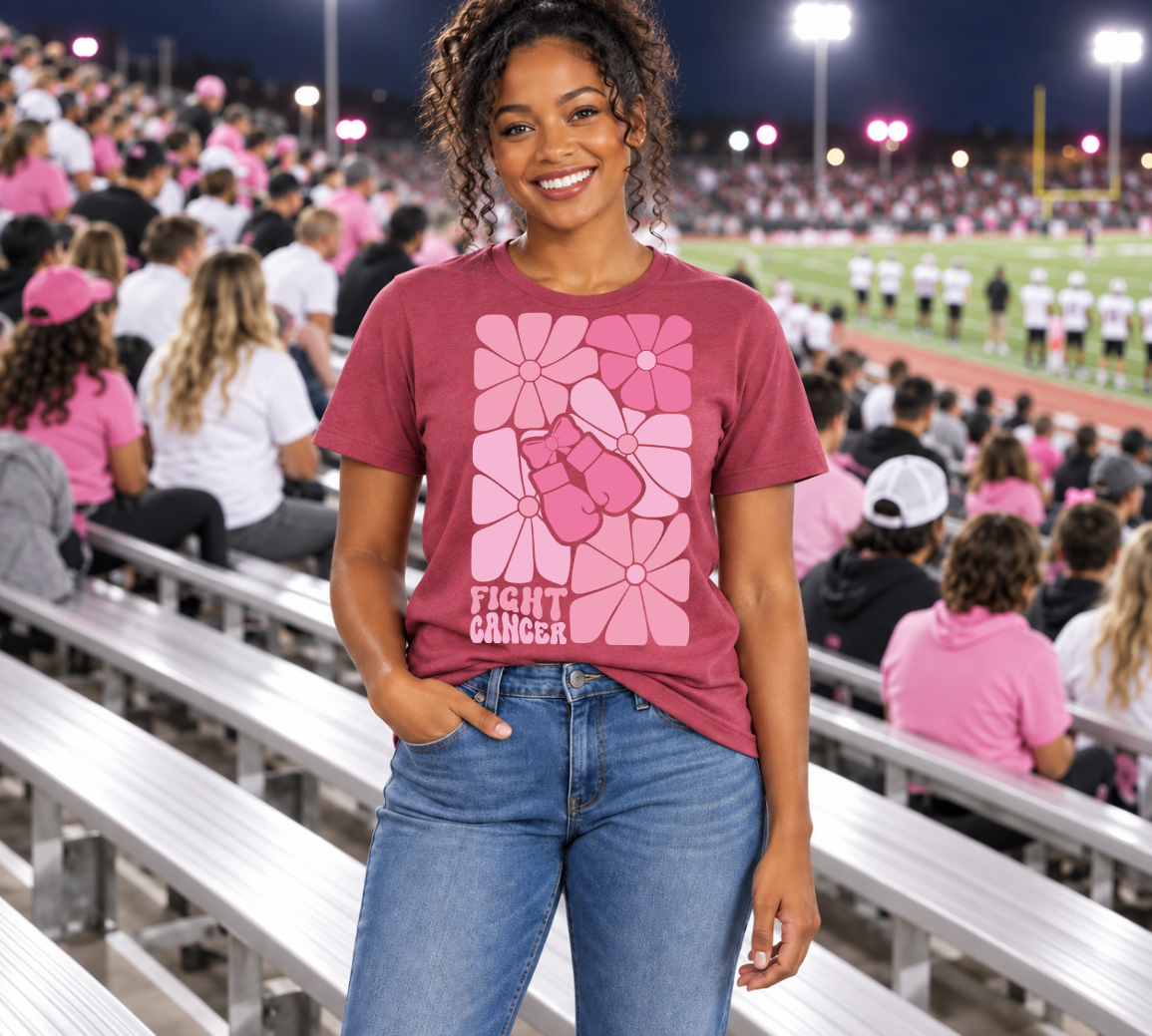 young african american woman standing in a football stadium, wearing a "fight cancer" t-shirt.