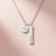 The Filled with Hope pendant necklace in silver stainless steel, resting on a soft pink background.