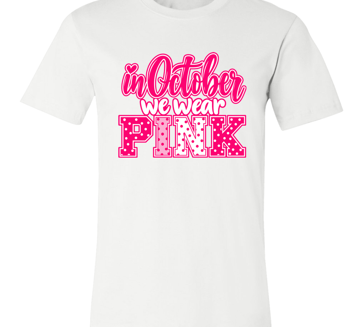 a white graphic t-shirt that reads 'in October we wear PINK' in pink and white lettering