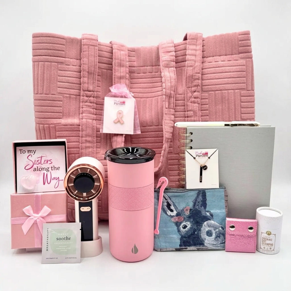 The Pink Luxe Box open and styled, showing 13 comfort, beauty, and recovery essentials curated for a woman facing breast cancer.
