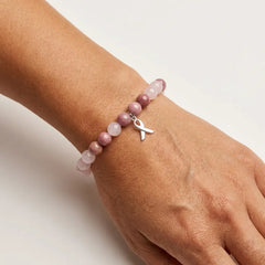 A natural stone beaded bracelet worn on a woman's wrist, with a stainless steel ribbon charm.