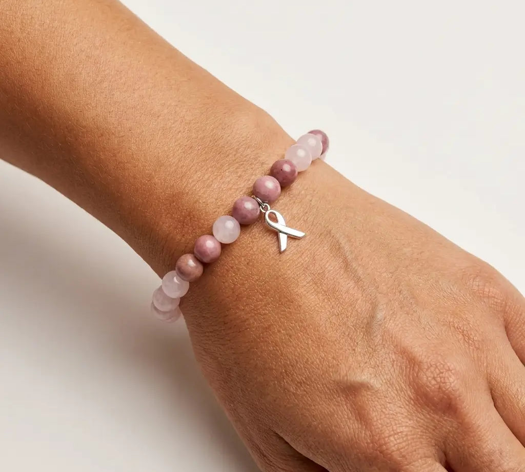 A natural stone beaded bracelet worn on a woman's wrist, with a stainless steel ribbon charm.