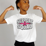 A child wearing a white graphic T-shirt with the words 'SUPPORT SQUAD' and a pink ribbon across the chest, posed with arms flexed against a plain light gray background.